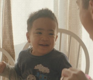 little boy learning how to walk with the help of his parents